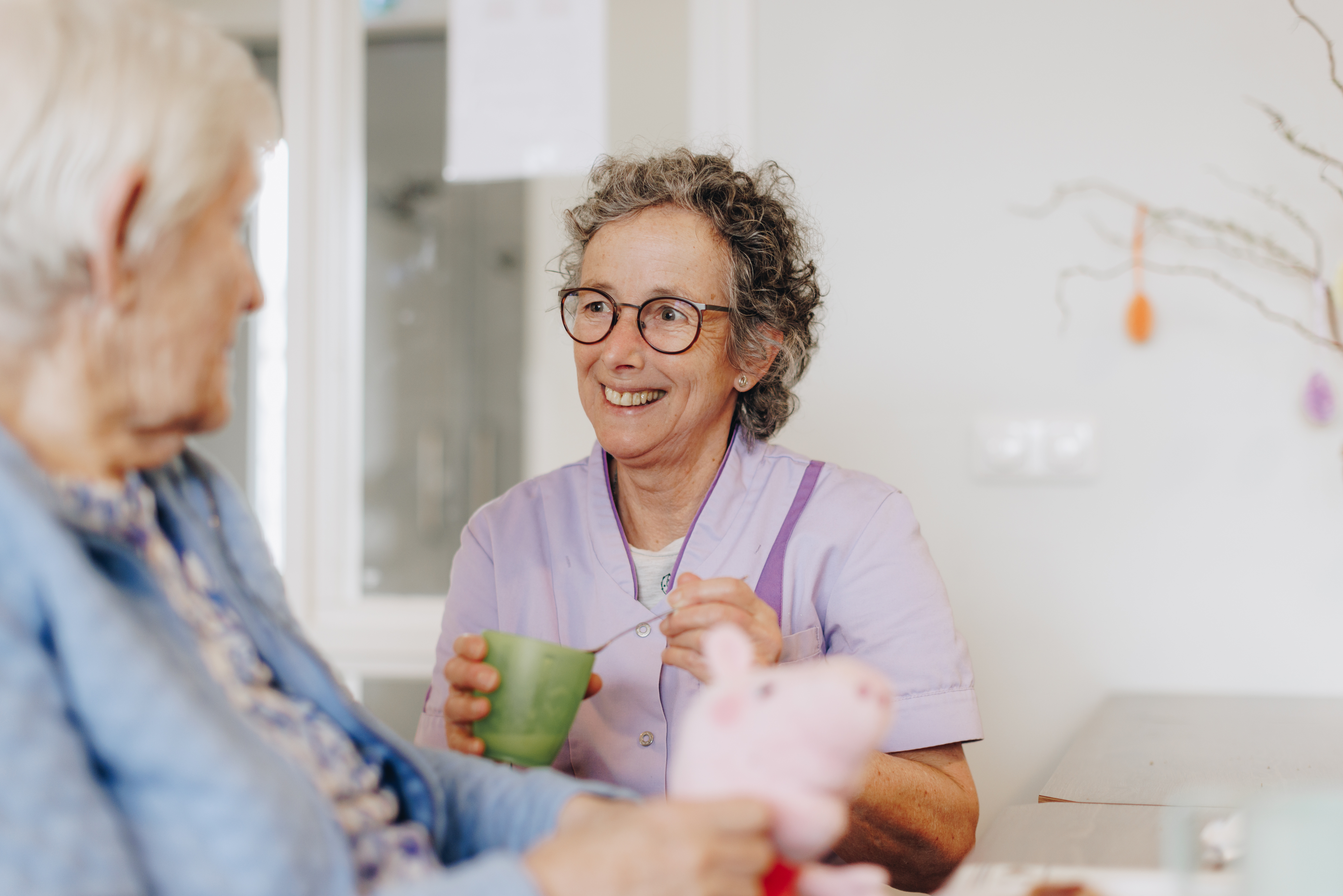 De Waterpoort Zorgpartners Bewoner Medewerker Eten Helpen Bord Tafel Rolstoel Interactie Lachen