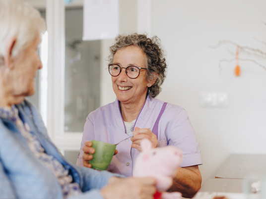 De Waterpoort Zorgpartners Bewoner Medewerker Eten Helpen Bord Tafel Rolstoel Interactie Lachen