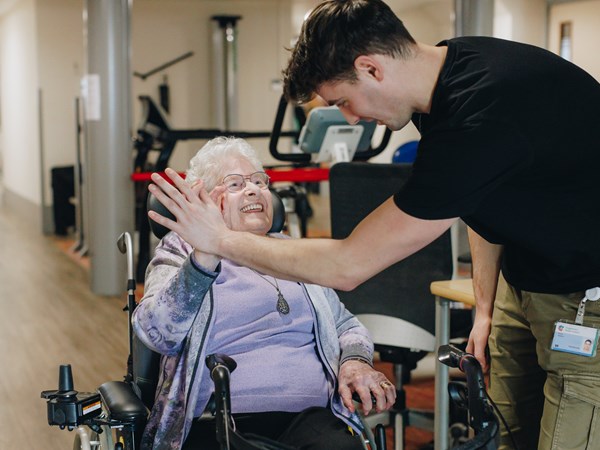 10 02 2023 Zorgpartners Savelberg Bewoner Fysiotherapeut Rolstoel Highfive Lachen