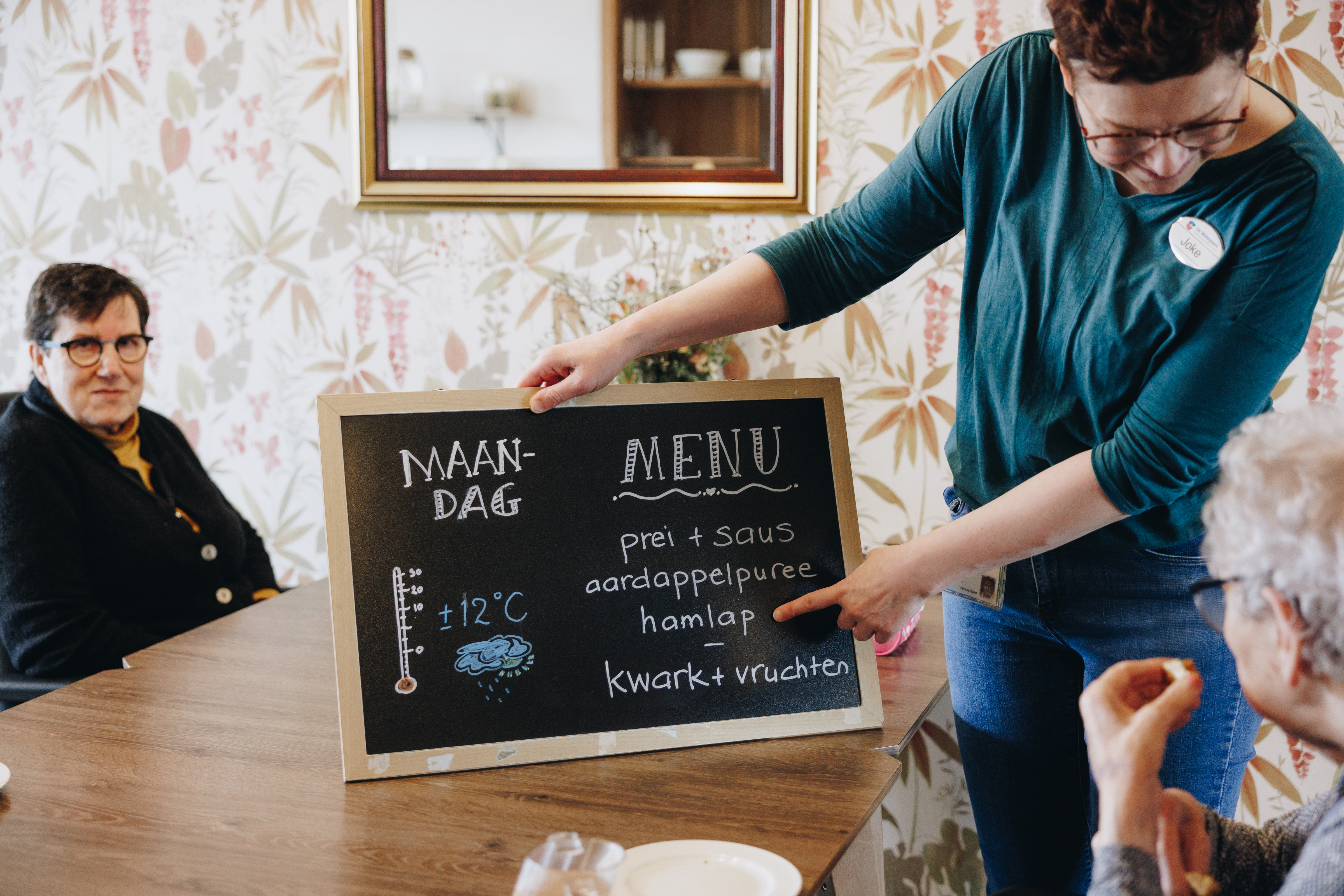 De Waterpoort Zorgpartners Woonkamer Tafel Bewoners Medewerker Menu Krijtbord